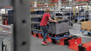 Käyttäjä lastaa puolikokoisella perävaunulla varustettua logistiikkajunaa