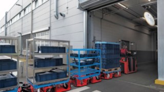 Linde MH:n LT10 WX -logistiikkajuna kuljettaa materiaalia kahden hallin välillä