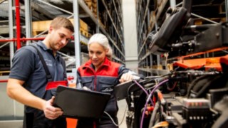 Kaksi Linde Material Handling -huoltoteknikkoa katselee kannettavaa tietokonetta trukin vieressä.