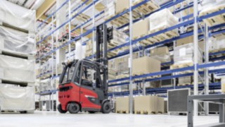 Linde E30 -sähkötrukki lastaa ja purkaa tavaroita hyllyn luona
