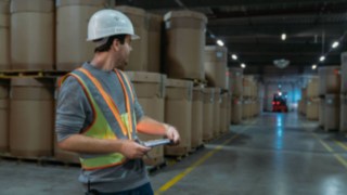 Warehouse worker wearing an interactive warning vest from Linde Material Handling in a poorly lit warehouse
