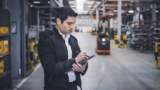 Linde Material Handlingin työntekijä tekee muistiinpanoja tabletilla varastossa.